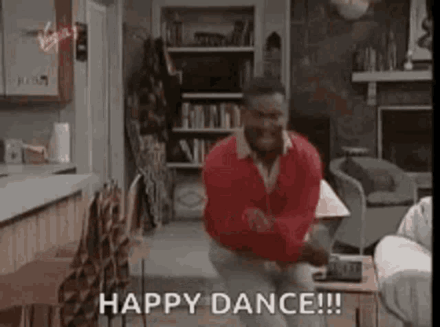 The man in the red sweater dances in a living room, captioned “HAPPY DANCE!!!”