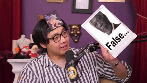 a man in a striped shirt is holding up a picture that says false