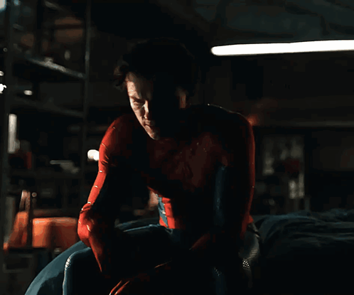 a man in a red shirt is looking down in the dark