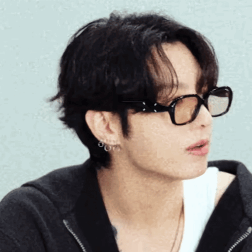 Jungkook wears black glasses in a close side-profile portrait.