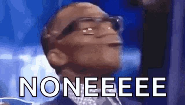 a man wearing glasses and a suit is making a funny face and saying noneeee .