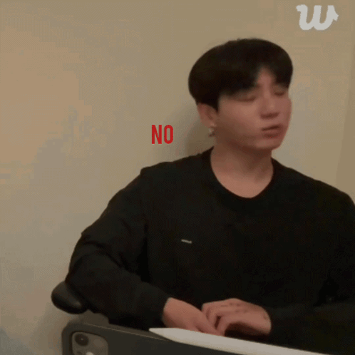 A seated man in black gestures beside a red “NO” caption.