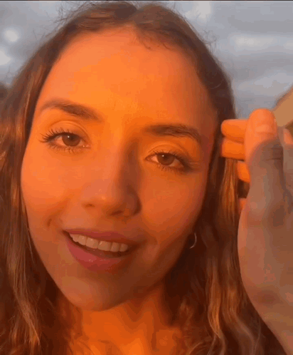 a close up of a woman 's face with a hand on her head