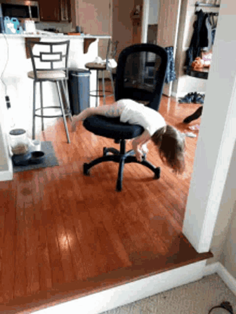A person idly spins in an office chair in a hallway.