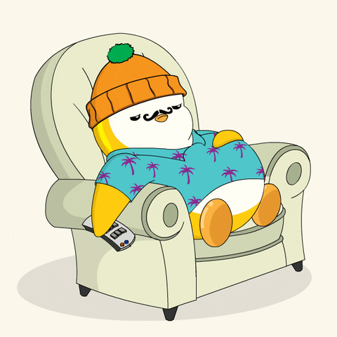 A bundled-up penguin naps in a recliner with a TV remote nearby.