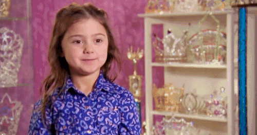 A young girl gives a deliberately creepy, mischievous smile.