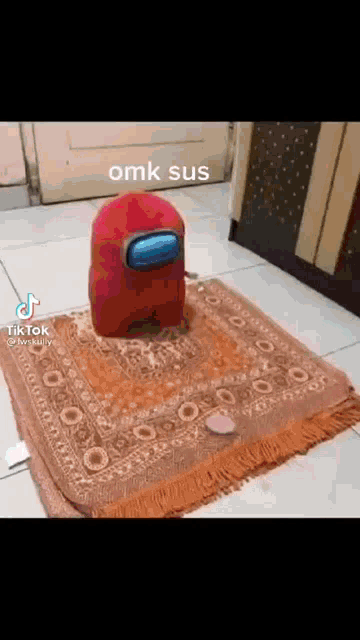 a red among us character is sitting on top of a prayer mat .