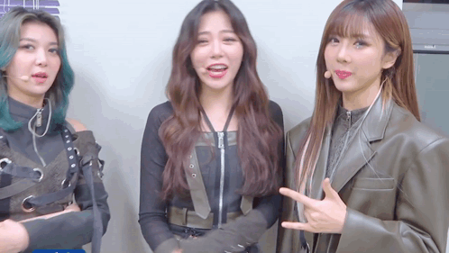 three girls are standing next to each other and one of them is pointing