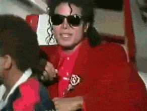 a man wearing sunglasses and a red jacket has a badge on his jacket