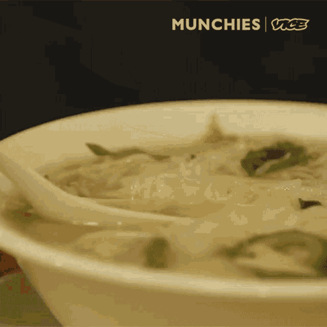 a close up of a bowl of soup with noodles and vegetables with a spoon in it .