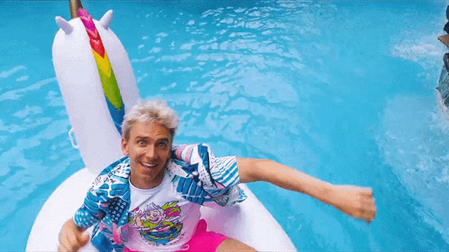 a man in a unicorn shirt is floating in a swimming pool