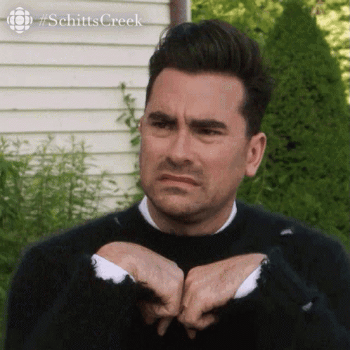 David Rose makes a skeptical expression while seated outdoors.