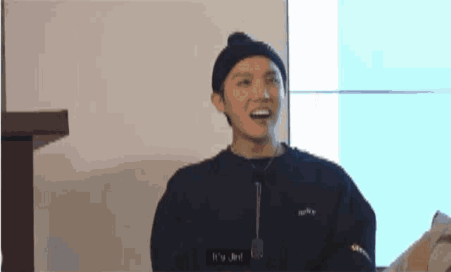 a man wearing a beanie and a sweater is smiling and talking .