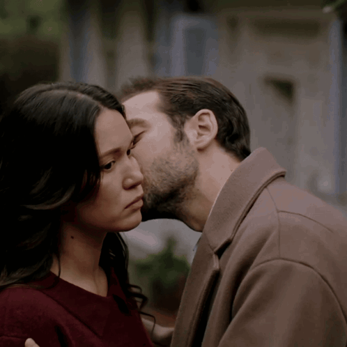 a man kissing a woman on the forehead in a close up