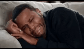 A man lies on a pillow crying with his face turned toward the camera.