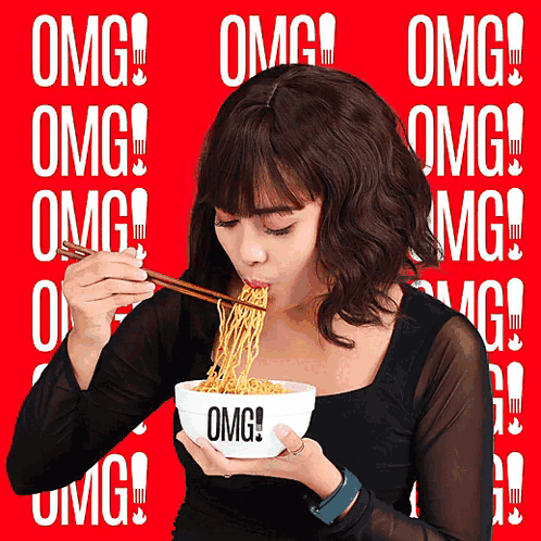 a woman eating noodles with chopsticks from a bowl that says omg