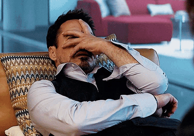 Tony Stark leans back and rubs his face in annoyance.