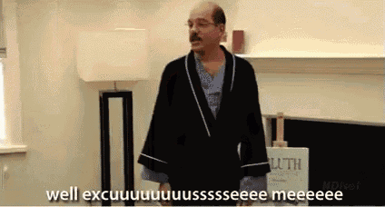 a bald man in a robe is standing in front of a fireplace and says well excuuuuuuussssseee meeeee