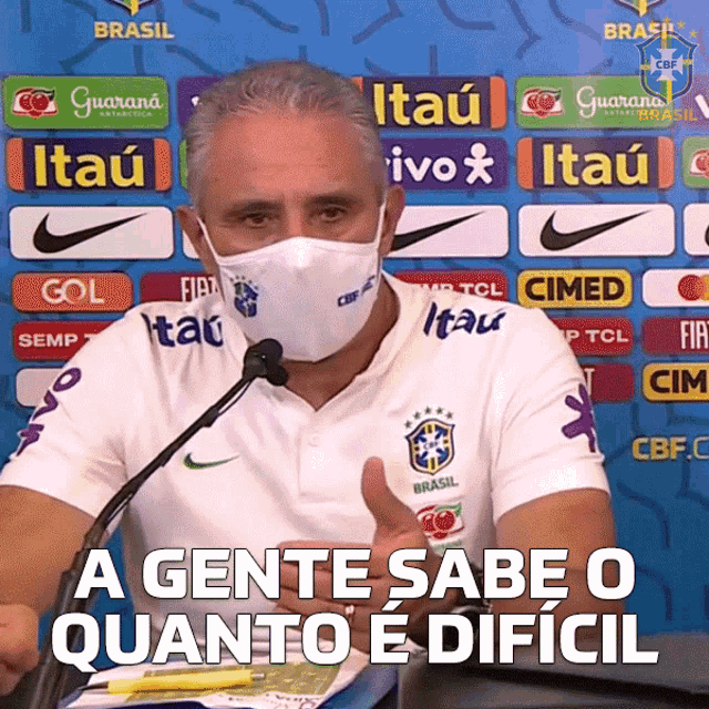a man wearing a face mask is giving a thumbs up in front of a sign that says brasil