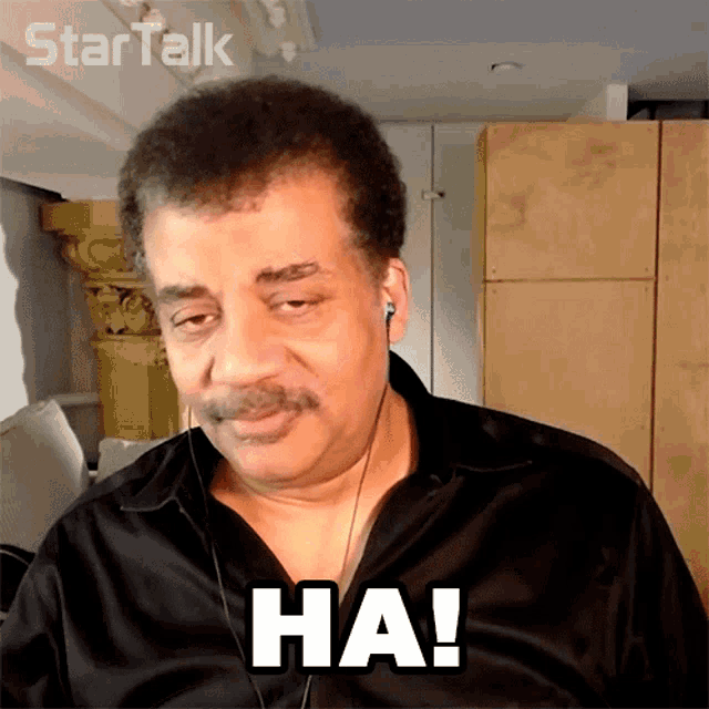 a man wearing ear buds and a black shirt says ha!