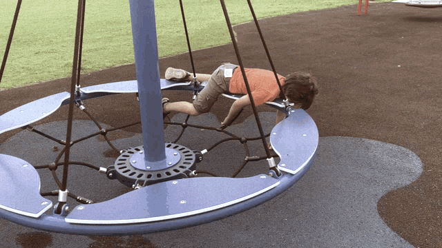 A child lies motionless on a playground spinning structure.