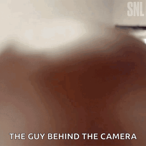 A blurry Saturday Night Live-style scene has the caption “THE GUY BEHIND THE CAMERA.”