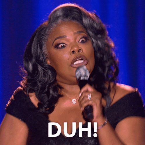 Mo’Nique holds a microphone onstage beneath a large “DUH!” caption.