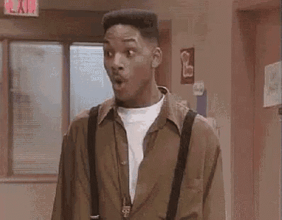 A young man reacts with a wide-eyed “oh snap” expression indoors.