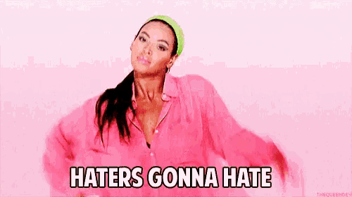 a woman wearing a pink shirt and a green headband says haters gonna hate .