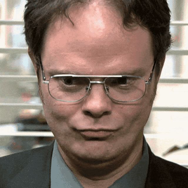 Dwight Schrute purses his lips in a dry, unimpressed reaction.