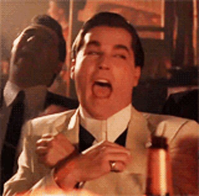 Ray Liotta laughs while seated at a restaurant table.