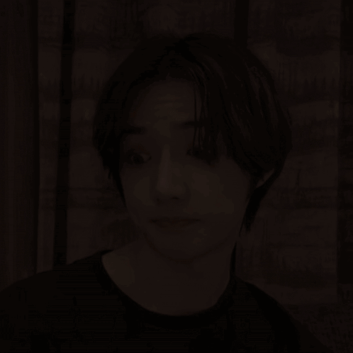 a young man with short hair is making a funny face while wearing a black shirt .