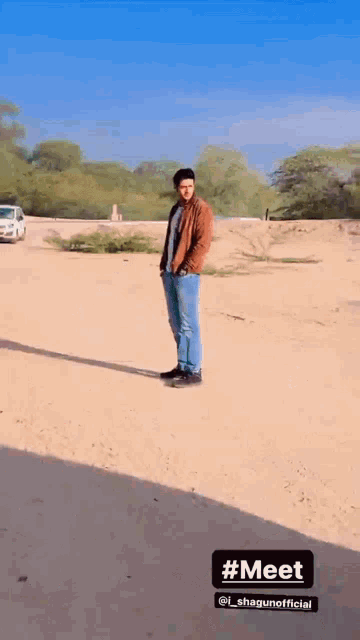 a man in a brown jacket is standing in a desert
