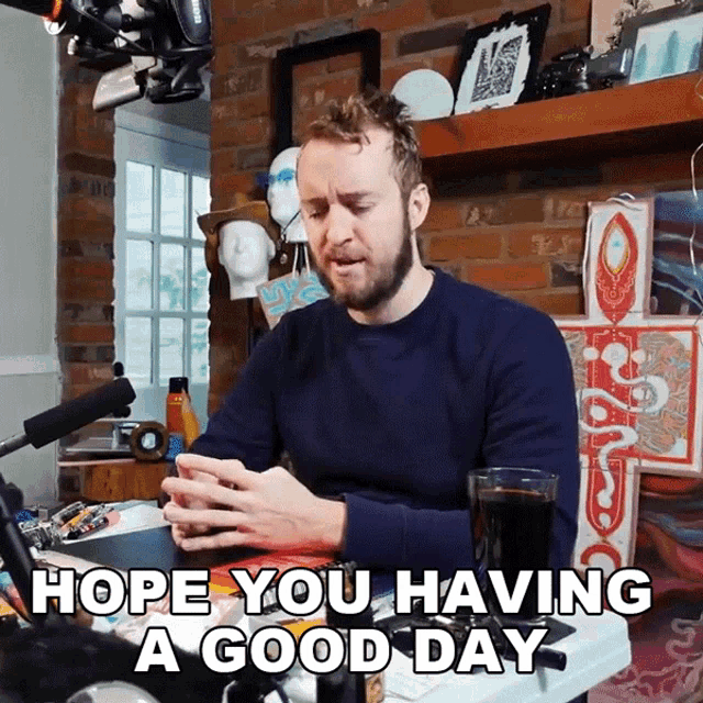 a man sitting at a table with the words hope you having a good day written below him