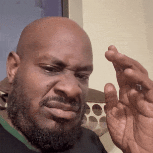 A bald man squints and grimaces in disgust.
