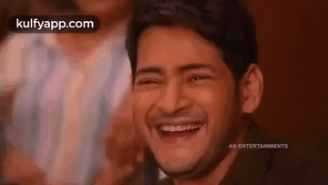 a man is laughing with his eyes closed in a crowd .