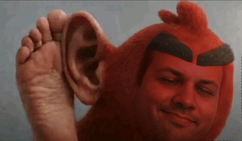 a man is wearing a red angry bird costume and has a large ear on his head .