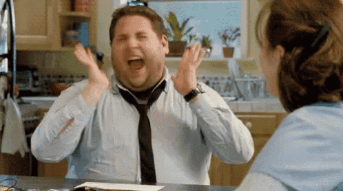 Jonah Hill throws his hands up and screams excitedly in an office.