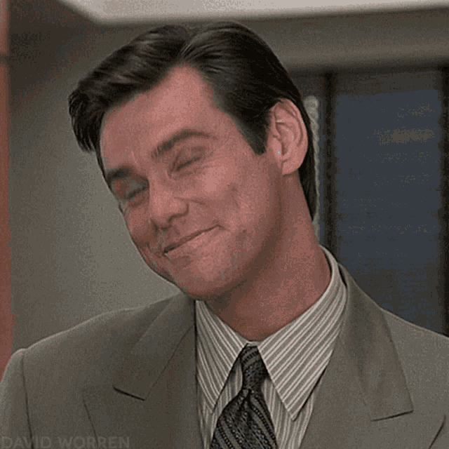 A man in a suit gives a knowing, sheepish smile.