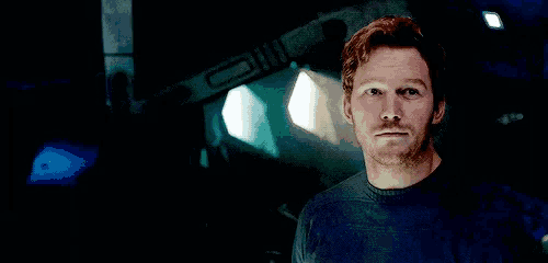 a man with a beard is standing in a dark room with a light shining on him .