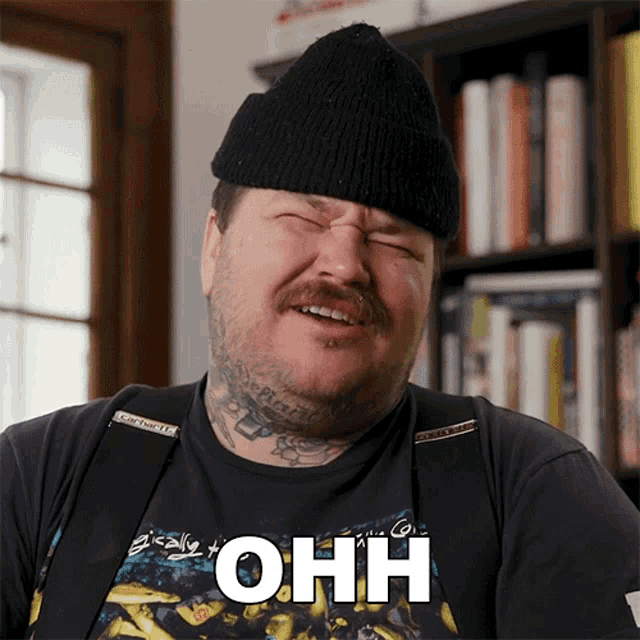 a man wearing a black beanie and suspenders has the word ohh on his shirt