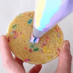 a person is holding a cookie with sprinkles and icing