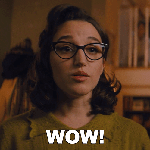 a woman wearing glasses and a green sweater has the word wow on her face