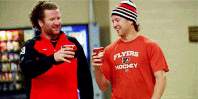 two men wearing flyers hockey shirts are talking