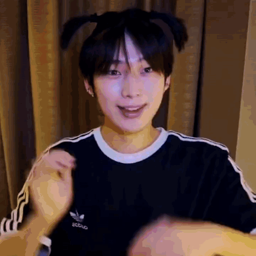 a young man wearing a black adidas t-shirt is making a funny face .