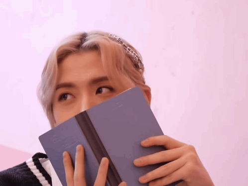 a person covering their face with a book which says ' i love you ' on the spine