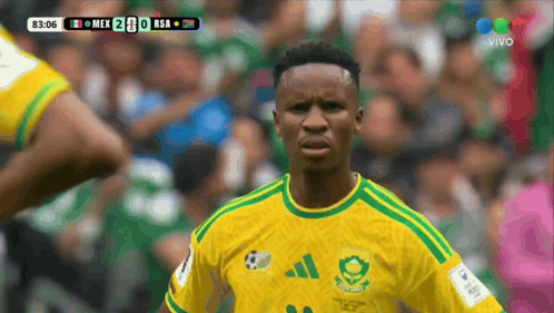 A soccer official in a yellow jersey looks confused on a crowded field.