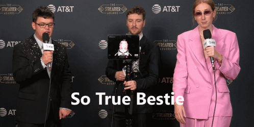 a woman in a pink suit is talking into a microphone in front of a streamer awards wall