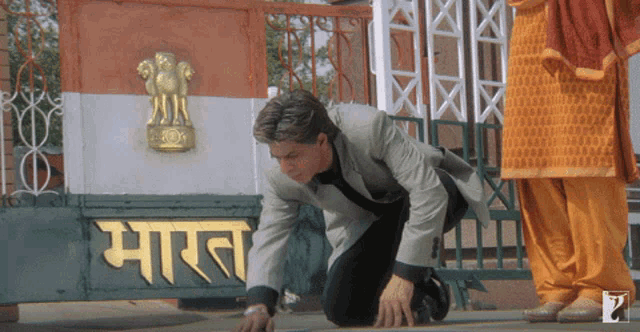 a man is kneeling down in front of a sign that says " भारत "