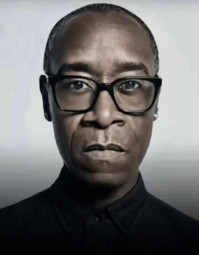 a man with glasses and a black shirt looks at the camera